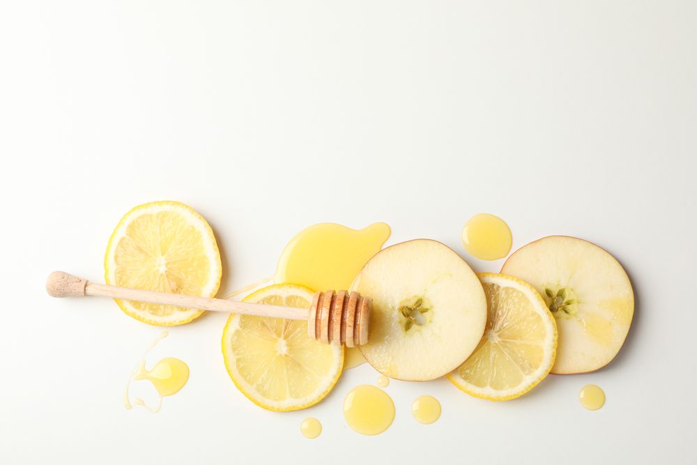 Dipper, honey, apple and lemon slices on blank background, top view