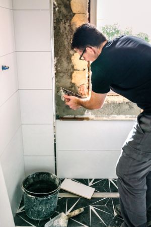 Bricklayer leveling cement with a trowel to tile the wall