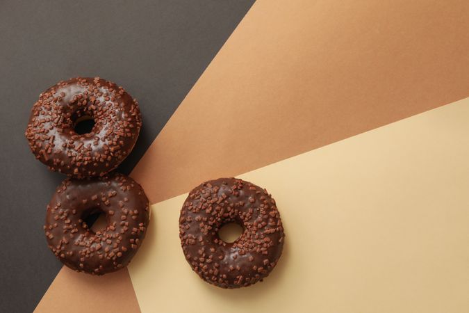 Tasty chocolate donuts on three tone background