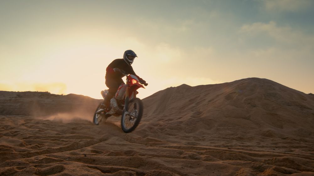 Professional Motocross Motorcycle Rider Driving Over the Dune and Further Down the Off-Road Track.