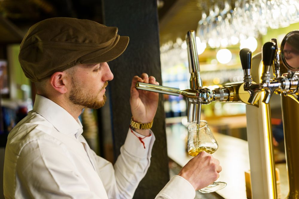Bartender pouring pint into glassware