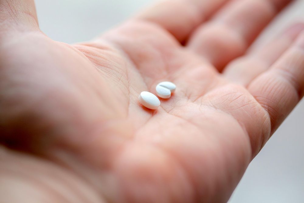 Hand holding two medication pills