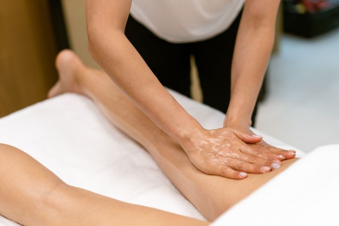 Masseuse giving a deep leg massage to a client