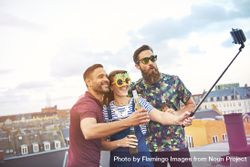 Group of friends with beer and funny glasses with selfie stick on rooftop 5qAAq5