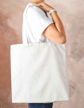 Young woman holding tote bag against brown background, empty space