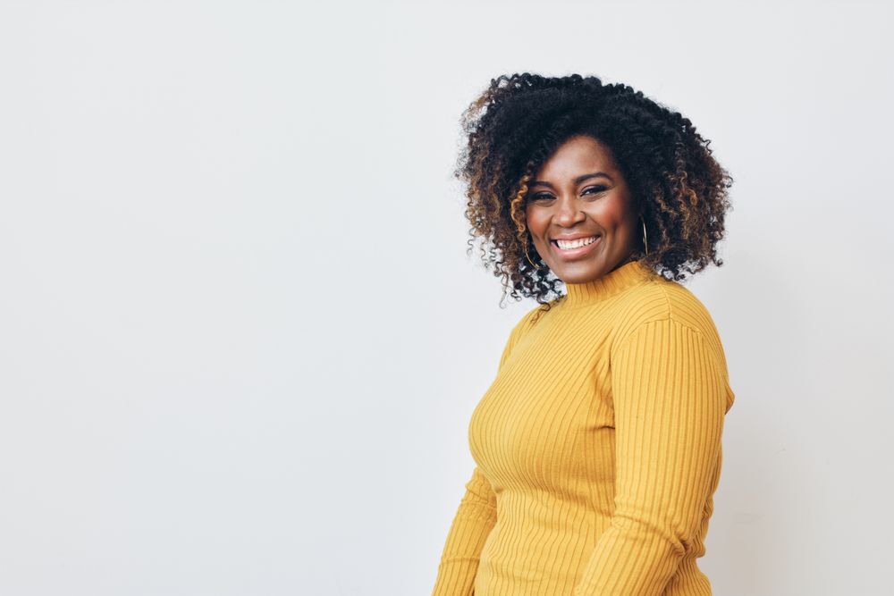 Studio shot of a confident Black woman in yellow shirt and bright room