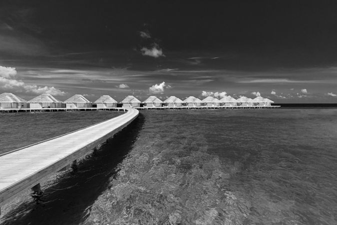 Monochrome walkway on crystal clear tropical water with overwater bungalows