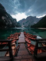 Brown wooden boats beside dock in a lake in The Fanes-Sennes-Prags Nature Park