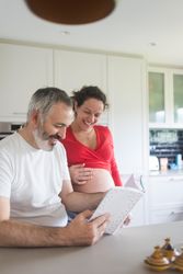 Laughing couple looking through book in kitchen