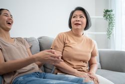 Asian mature mother telling joke to her daughter