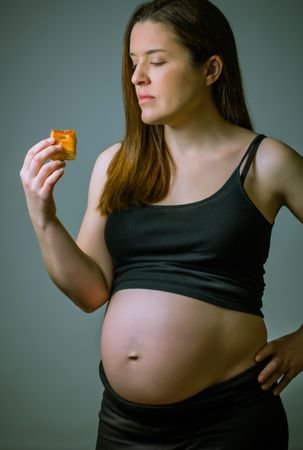 Pregnant women showing her belly and ready to eat cake