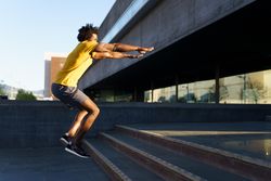Man doing jump squats on stairs outside