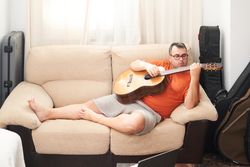 a man relaxing on the couch playing guitar