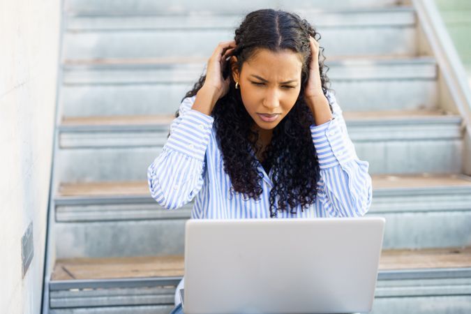 A young woman feeling stressed and anxious as she struggles with frustrating laptop issues