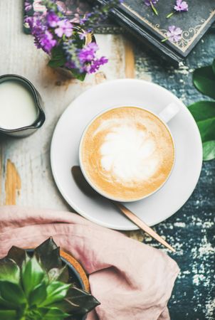 Top view of latte on saucer with cream on side