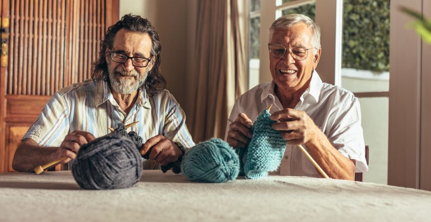 Two men knitting at home