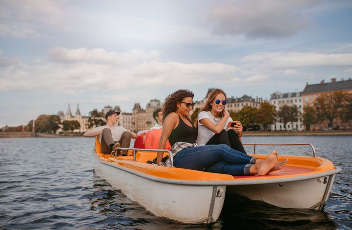 Two young women friends sitting on front of pedal boat