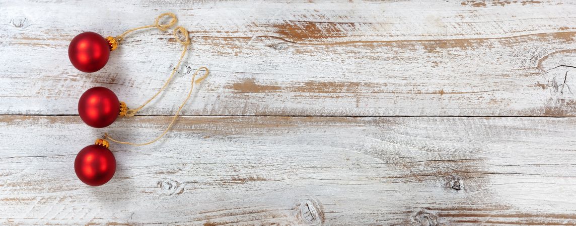Three red Christmas ball ornaments on rustic wooden background
