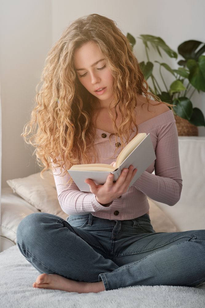 Pensive female in casual clothes reading novel at home