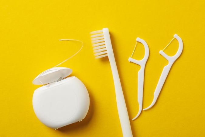 Tools for dental care on yellow background, top view