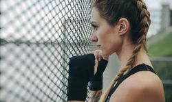 Sportswoman looking through a fence