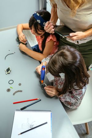 Students working with machine pieces next to teacher in robotics class