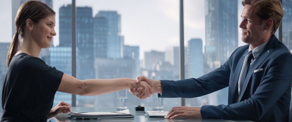 Female and Male Business Partners Sign Successful Deal and Shake Hands in Meeting Room in Skyscraper Office.