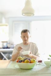 Man Chewing a Bite of Oats While Sitting an his Dinning Table.