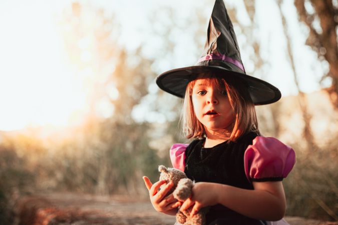 Surprised girl dressed as a witch in costume at sunset