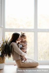 Mother her young daughter beside window 0ydaGb