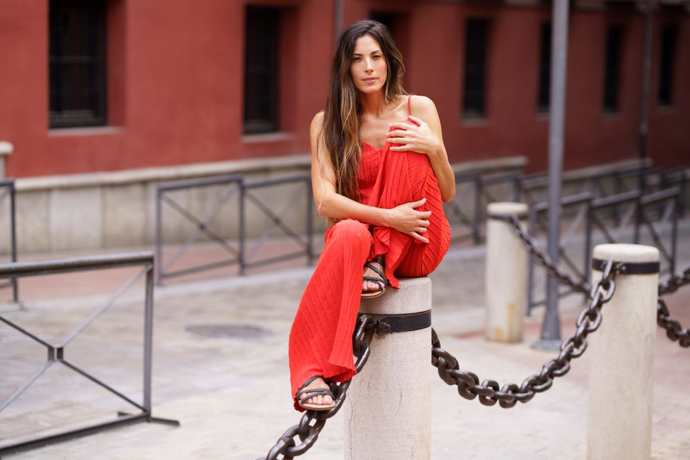 An Elegant Woman Wearing a Stunning Red Fashion Outfit Posing Gracefully Outdoors in Nature