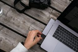 Man with tattooed hands with camera and laptop
