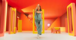 Portrait of Young Woman Sitting in Geometric Abstract Environment, Dancing with Hypnotic Graceful Movements. Static Camera Capturing Fashionable Female Dancer in Colorful Studio