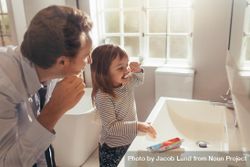 Dad teaching his daughter how to brush teeth 0JYvnb