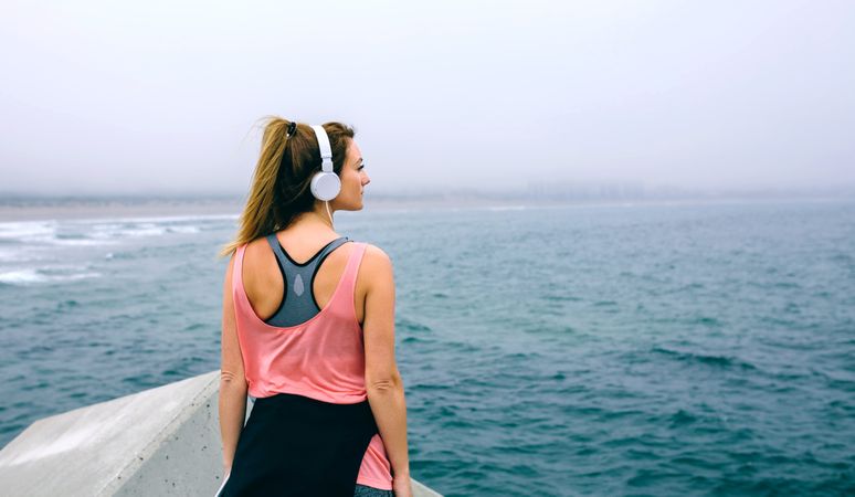 Sportswoman with headphones watching the sea