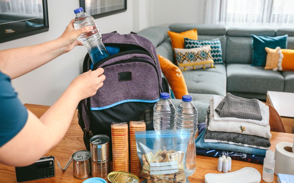 Woman putting a water bottle to prepare emergency backpack