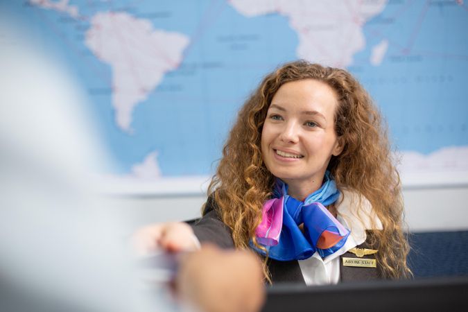 Woman working in airport holding guest’s passport at check in