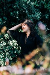 Smiling female looking out of green bushes