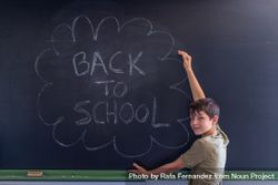 Boy standing at chalkboard with "back to school" 0gEP84