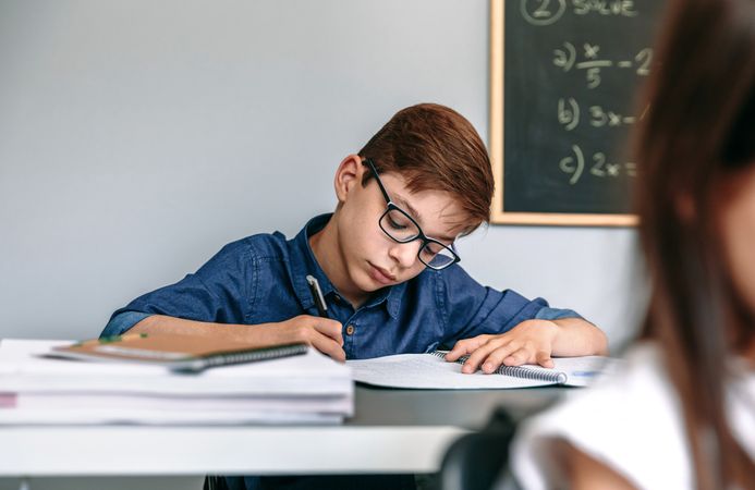 Boy writing in notebook at school