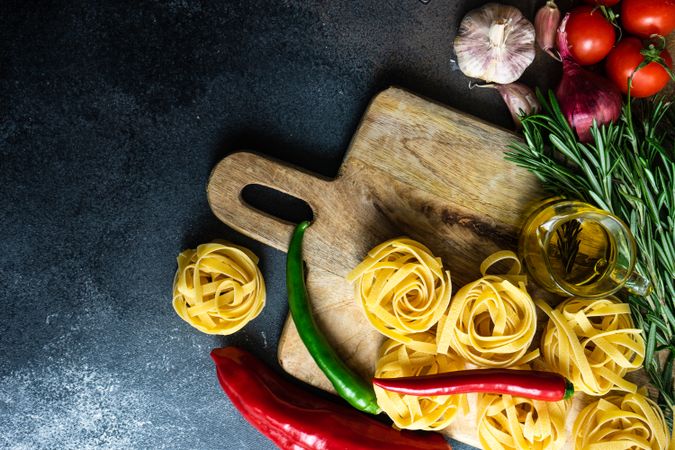 Raw homemade Fettuccine pasta and ingredients on stone rustic background with copy space