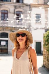 Woman in hat walking along sunny street