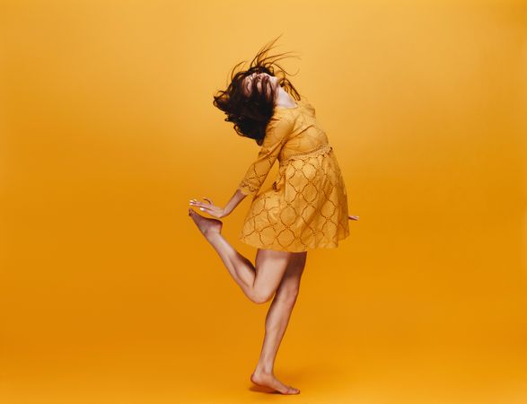 Beautiful young woman dancing over orange background