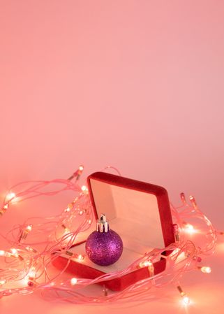 Jewelry box with Christmas bauble inside surrounded by fairy lights