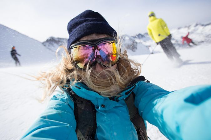 Woman taking selfie on mountain in ski goggles