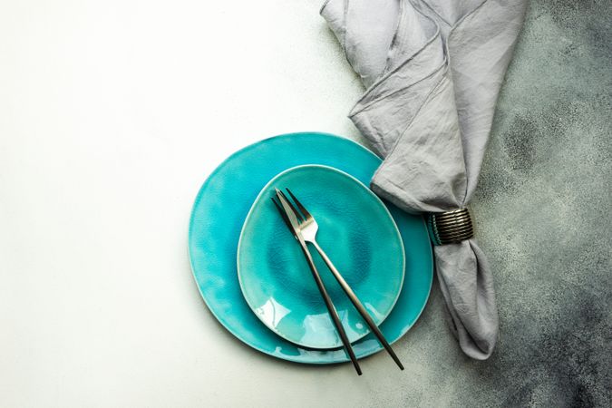 Top view of modern bright teal plates with silverware