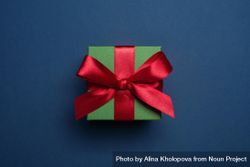 Green present wrapped with red bow on blue background 0W6orb