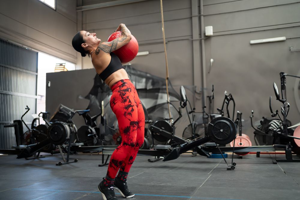 Strong woman exercising using medicinal ball in a gym