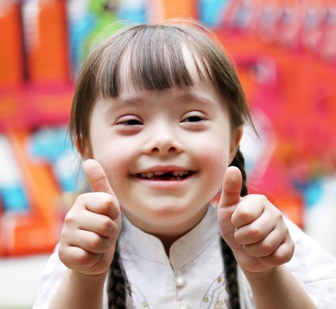 Smiling young girl with braided hair making the thumbs up sign