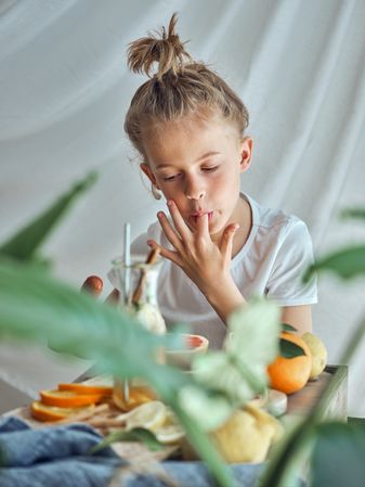Boy licking finger at table with fruits